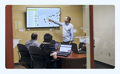 Four People in Office Looking at Screen.